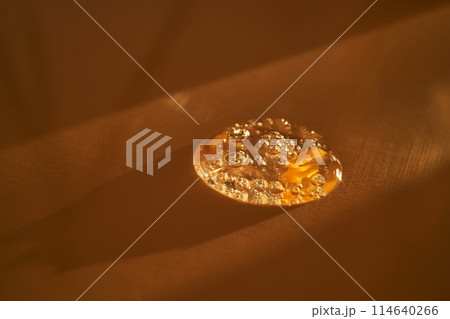 Drop of serum shimmering in the sun on a beige background. Drop of serum shimmering in the sun on a beige background. 114640266