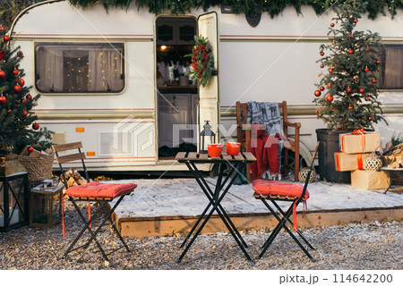 Caravan mobile home with terrace, Mobile home decorated with Christmas decor. Festive atmosphere - lights, red blankets, Christmas trees. Caravan camping. mobile home trailer. Selective focus Caravan mobile home with terrace, Mobile home decorated with Christmas decor. Festive atmosphere - lights, red blankets, Christmas trees. Caravan camping. mobile home trailer. Selective focus 114642200