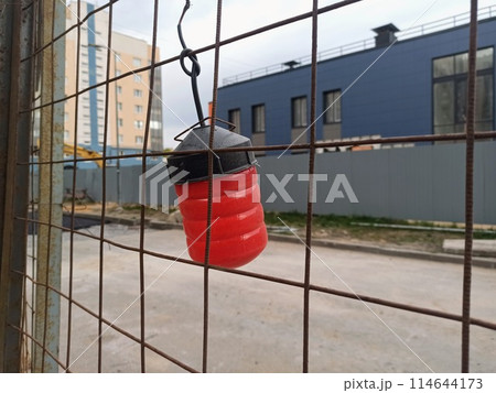 Hanging red buoy on the fence of a building construction site. 114644173