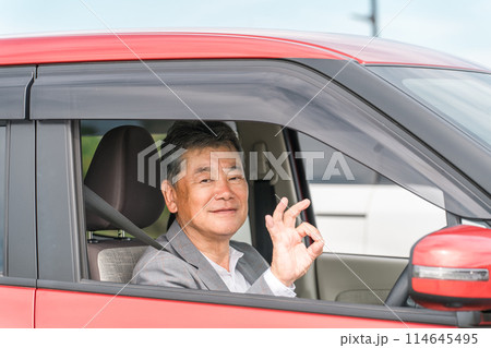 自動車の運転をする笑顔の高齢者ドライバーの男性 114645495