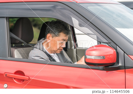 自動車の運転中に居眠りをする高齢者ドライバーの男性 自動車の運転中に居眠りをする高齢者ドライバーの男性 114645506