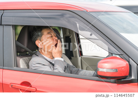自動車の運転中に眠気を感じてあくびをする高齢者・シニア男性 自動車の運転中に眠気を感じてあくびをする高齢者・シニア男性 114645507