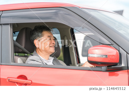 自動車の運転をする笑顔の高齢者ドライバーの男性 114645512