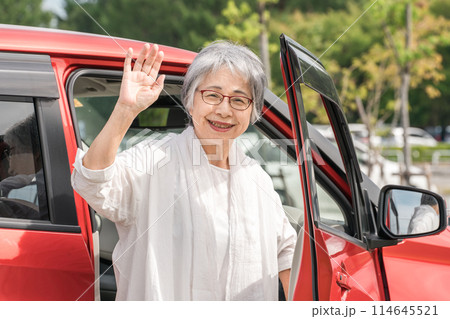 自動車から降りて手を振る・挨拶する高齢者ドライバー女性 114645521