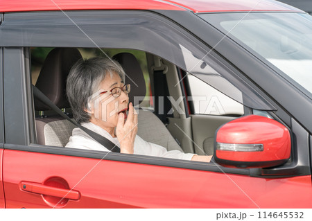自動車の運転中に眠気を感じてあくびをする高齢者・シニア女性 自動車の運転中に眠気を感じてあくびをする高齢者・シニア女性 114645532