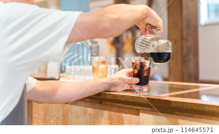 カフェ・飲食店のカウンターでコーヒをグラスに注ぐ店員・キッチンスタッフの男性 カフェ・飲食店のカウンターでコーヒをグラスに注ぐ店員・キッチンスタッフの男性 114645571