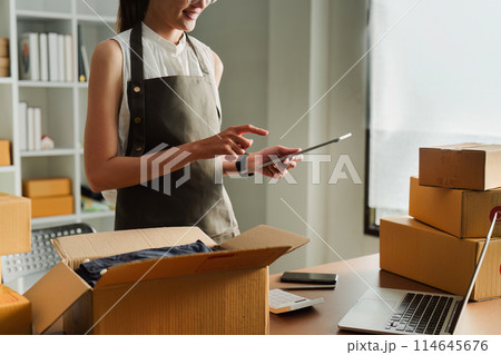Young business entrepreneur using laptop. Preparing for shipping, online selling, e-commerce concept 114645676