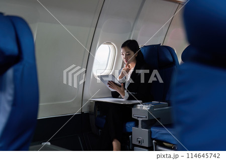 Beautiful Asian businesswoman working with tablet in aeroplane. working, travel, business concept Beautiful Asian businesswoman working with tablet in aeroplane. working, travel, business concept 114645742