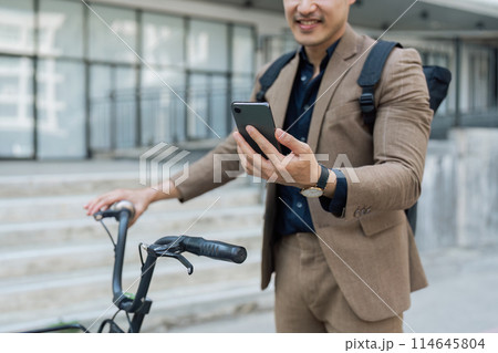 asian young businessman use smart phone while commuting in city. Eco friendly asian young businessman use smart phone while commuting in city. Eco friendly 114645804