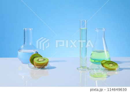 Unique designing template for kiwi research theme photo, lab glassware contains kiwi essence and fresh kiwi fruit over light blue background with blank space for displaying product or adding text Unique designing template for kiwi research theme photo, lab glassware contains kiwi essence and fresh kiwi fruit over light blue background with blank space for displaying product or adding text 114649630