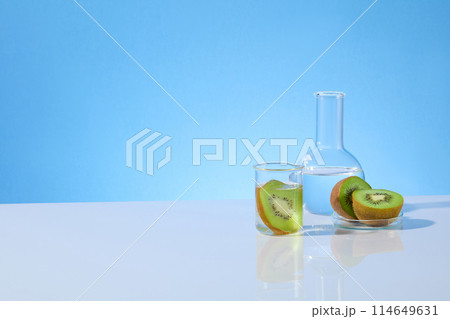 Kiwi and laboratory theme photograph with a few instruments in lab containing kiwi featured on the right side of white table, vacant left side space, over blue texture. Front view, copy space Kiwi and laboratory theme photograph with a few instruments in lab containing kiwi featured on the right side of white table, vacant left side space, over blue texture. Front view, copy space 114649631