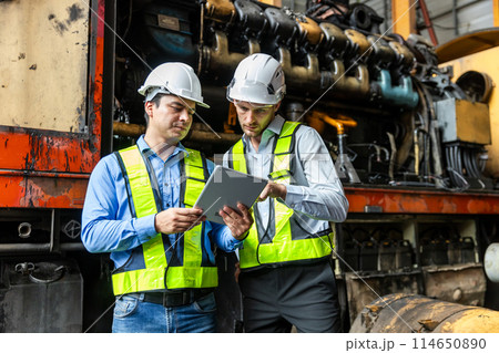 Railway technician engineer wearing safety uniform and safety helmet holding tablet and blueprint. 114650890