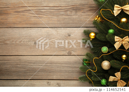 Christmas decoration. Fir-tree branch with green and gold balls on grey background Christmas decoration. Fir-tree branch with green and gold balls on grey background 114652541