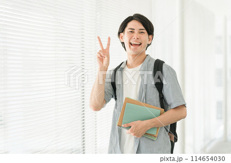 大学・学校の廊下にいるピースする笑顔の大学生のアジア人男性（学生・塾・予備校） 114654030