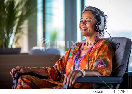 Woman in wheelchair listening music in headphones 114657906