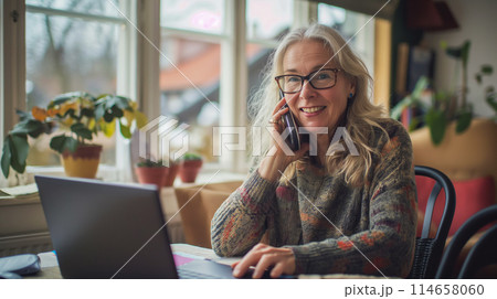 Adult woman from Norway talking on the phone, businesswoman freelancing from a cafe, laptop standing on the table in front of her, copy space for concept Adult woman from Norway talking on the phone, businesswoman freelancing from a cafe, laptop standing on the table in front of her, copy space for concept 114658060