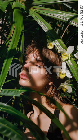 Portrait of a beautiful young woman with orchids in her hair standing in the jungle among palm leaves, the sun's rays through the foliage illuminate the model's face, earth day poster 114658287