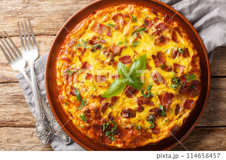 Crustless pie with bacon, egg, chicken, basil and cheese close-up on a plate. Horizontal top view Crustless pie with bacon, egg, chicken, basil and cheese close-up on a plate. Horizontal top view 114658457