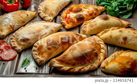 Italian traditional baked calzone with tempting fillings and ingredients on wooden table, food delivery 114658741