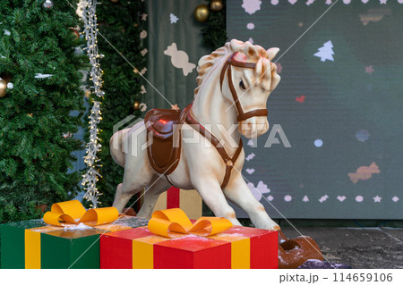 white baby horse a white baby horse next to a Christmas tree and gift boxes. New Year decorations 114659106