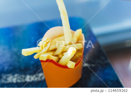 Crispy and Delicious Golden French Fries Served in a Paper Cup on a Wooden Table 114659162