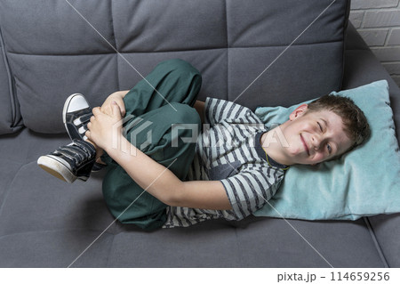 boy of school age is lying on the sofa and fooling around smiling boy of school age is lying on the sofa and fooling around smiling 114659256