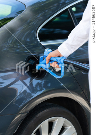 Man holds a hydrogen fueling nozzle. Refueling car with hydrogen fuel. Concept Man holds a hydrogen fueling nozzle. Refueling car with hydrogen fuel. Concept 114662507