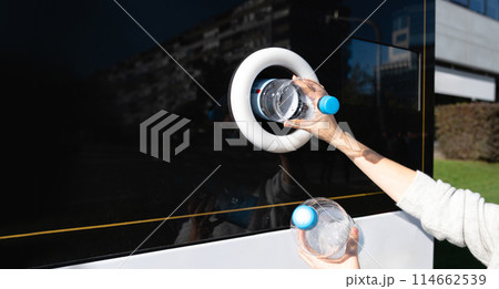 Woman uses a self service machine to receive used plastic bottles and cans on a city street.. Woman uses a self service machine to receive used plastic bottles and cans on a city street.. 114662539