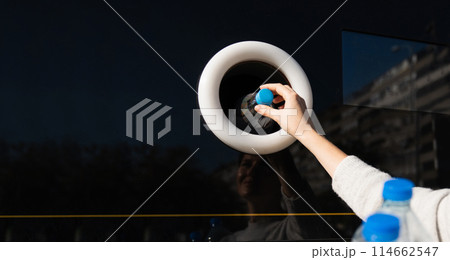 Woman uses a self service machine to receive used plastic bottles and cans on a city street.. Woman uses a self service machine to receive used plastic bottles and cans on a city street.. 114662547