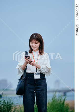 スマホを操作しながら歩く若い女性 スマホを操作しながら歩く若い女性 114663612