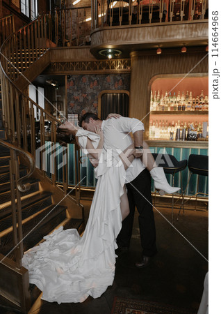 A young couple in wedding looks posing in a stylish loft bar. A young couple in wedding looks posing in a stylish loft bar. 114664968