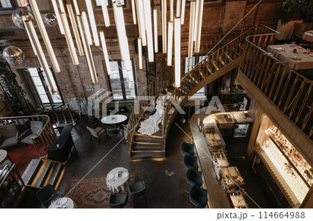 A young couple in wedding looks posing in a stylish loft bar. A young couple in wedding looks posing in a stylish loft bar. 114664988