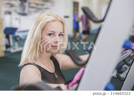 Attractive blonde stands near squat frame in gym 114665522