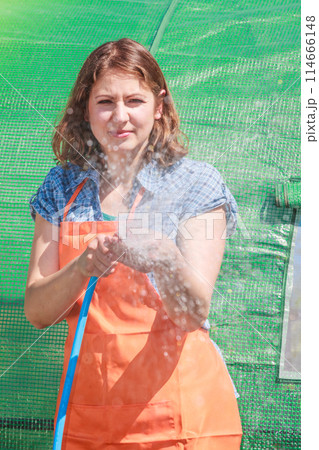 Woman watering the garden with hose Woman watering the garden with hose 114666148