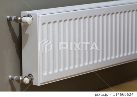 White heating radiator with thermostat valve on wall in an apartment interior after renovation works. White heating radiator with thermostat valve on wall in an apartment interior after renovation works. 114666624