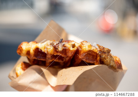 Hand holding Croffle with truffle. It is a hybrid of a croissant and waffle which is a popular pastry in South Korea 114667288
