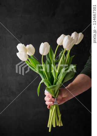 A male hand holds a bouquet of white tulips 114667301
