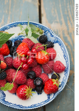 Raspberries, strawberry and wild blackberries on a vintage plate 114667489