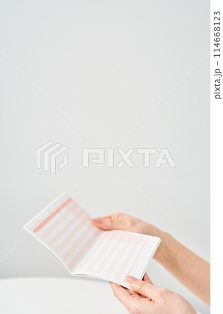 銀行の通帳を見る女性の手元 銀行の通帳を見る女性の手元 114668123