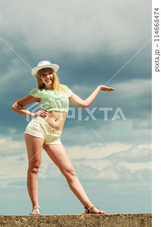 Summer girl showing open hand against sky 114668474