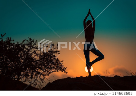 Silhouette of a yogi during sunset yoga on a hilltop 114668693