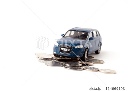 Blue toy iron car with coins on a white background. concept of earnings, income and high cost Blue toy iron car with coins on a white background. concept of earnings, income and high cost 114669198