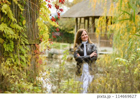 A young beautiful girl walks in the forest near a pond and looks happily into the frame A young beautiful girl walks in the forest near a pond and looks happily into the frame 114669627