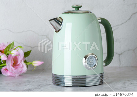 Green stylish electric teapot with roses in background. 114670374