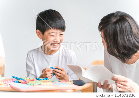 学校の教室でアルファベットのおもちゃを使って英語を勉強する小学生低学年の男の子と女性教師 114672830