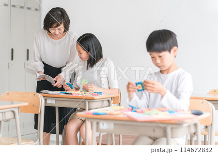 学校の教室で英語を勉強する小学生の男女と女性講師（先生） 114672832