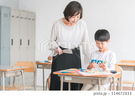 学校の教室で英語を勉強する男の子と女性講師（先生） 114672833