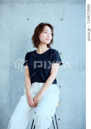 コンクリート背景に椅子に座った女性 114672999
