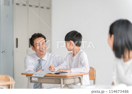 学校の教室・塾で男子生徒に勉強を教える男性教師・塾講師・先生（小学校・学童・学童保育・教育） 114673486