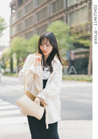 バッグの中をガサゴソする若い女性 バッグの中をガサゴソする若い女性 114675402